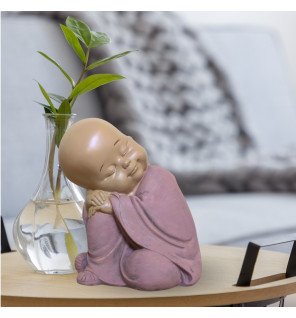  figurine décorative représentant un bébé bouddha rose en méditation sur une table en bois clair