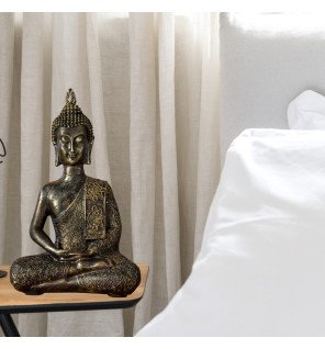  statue décorative de bouddha en résine grise sur une table basse entourée de plantes vertes