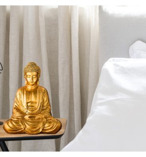  ambiance relaxante avec la statue bouddha dorée placée près d’un coussin de méditation