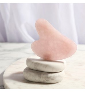 accessoire de massage visage en pierre naturelle sur une table en bois clair