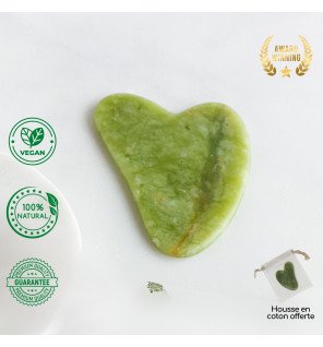 gua sha en pierre de jade vert dans une ambiance spa avec bougies allumées