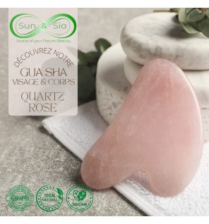 main utilisant le guasha en quartz rose sur la joue pour masser la peau