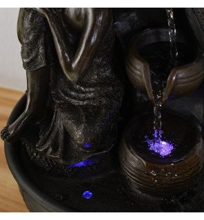  fontaine bouddha posée près de plantes vertes pour une atmosphère relaxante