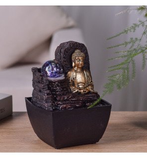  fontaine bouddha placée sur une étagère avec plantes vertes et livres