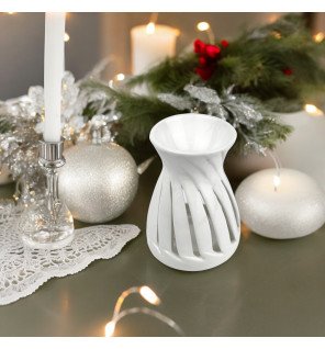  le brûle-parfum corta blanc placé sur une étagère avec des livres et des objets déco