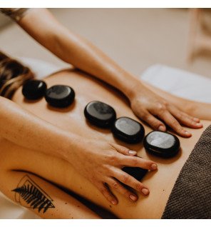  gros plan sur une main plaçant une pierre chaude sur le dos d’une personne