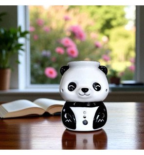  brûle-parfum en céramique panda placé sur une étagère avec des plantes vertes autour