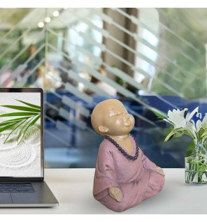 sculpture raffinée représentant un bébé bouddha rose en pleine réflexion dans un intérieur lumineux